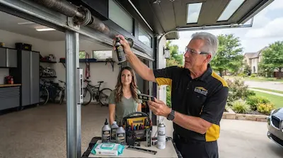 garage door technician performing maintenance and lubrication in Garland TX