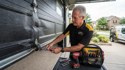 garage door technician repairing spring and panel in Garland TX